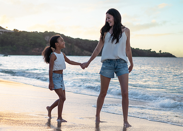 a woman and a girl holding hands on a beach