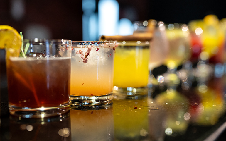 a group of glasses with different colored drinks