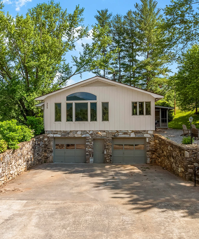 a house with a stone wall and trees