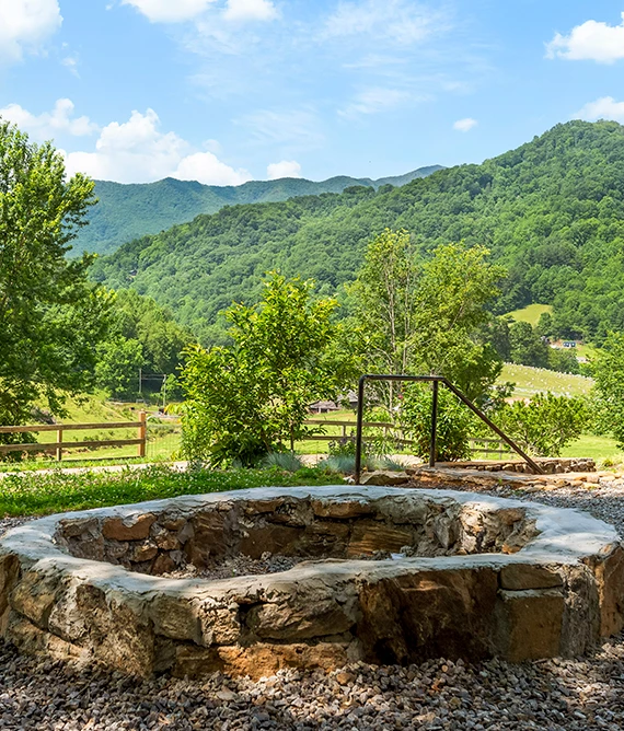 a stone pit with a fence and trees in the background