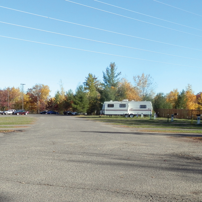 a parking lot with a trailer and cars in the background