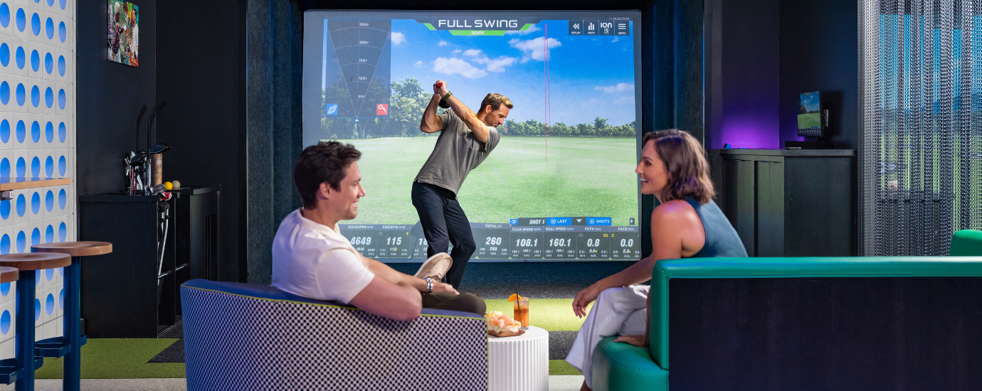 a man playing golf with people sitting in chairs
