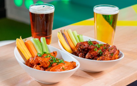 two bowls of chicken wings and vegetables