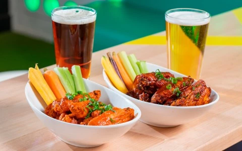 two bowls of chicken wings and vegetables