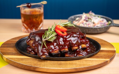 a plate of ribs with sauce and a drink