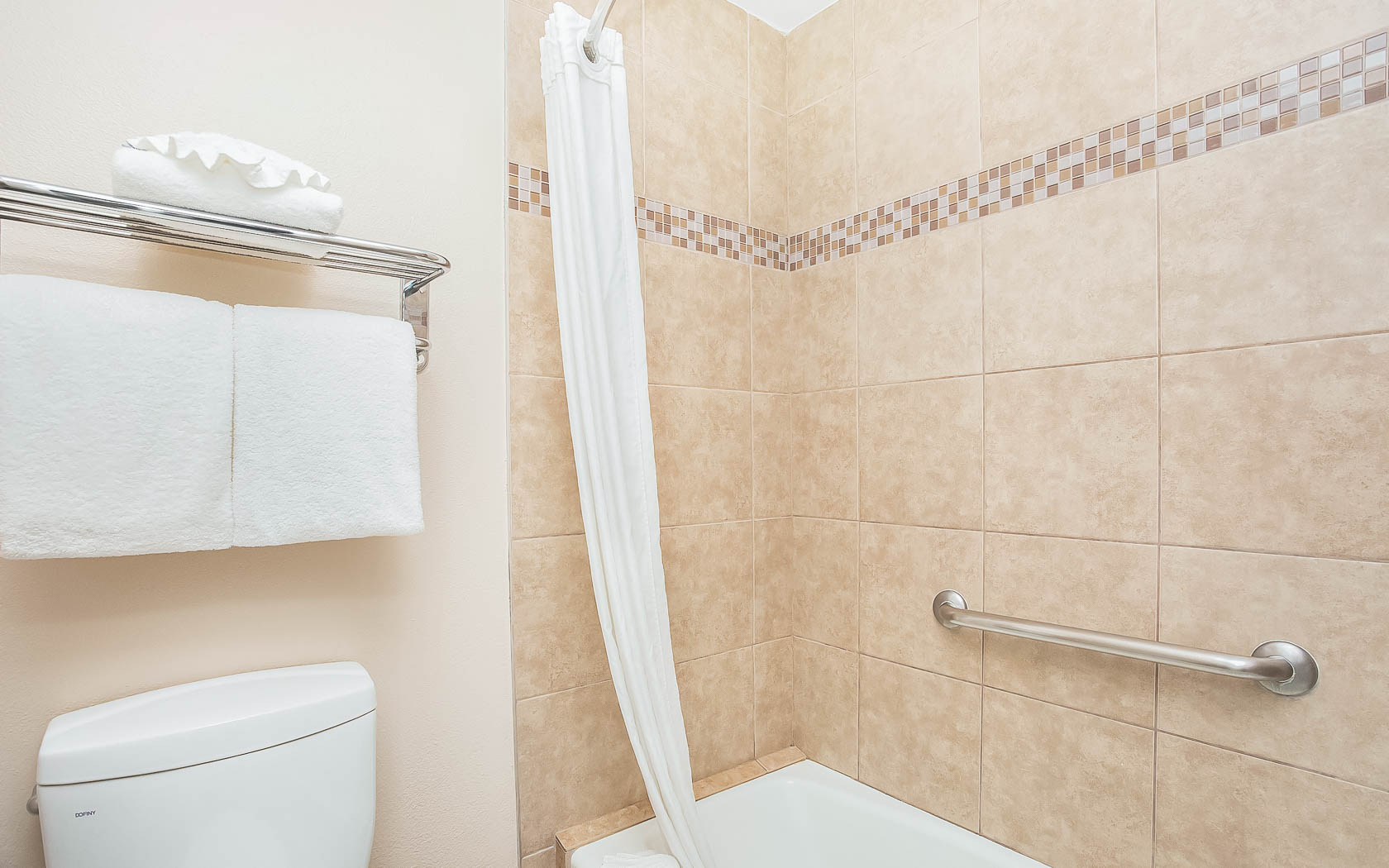 tub shower with brown tiles and white toilet