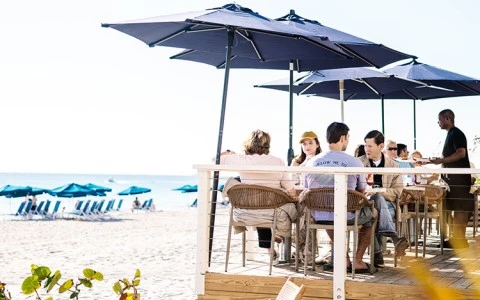 a group of people sitting at a table on a beach