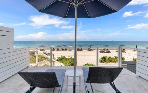 chairs and umbrella on a deck overlooking the ocean
