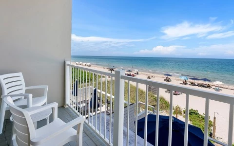 a balcony with chairs and a beach view
