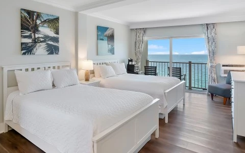 a room with two beds and a balcony overlooking the ocean
