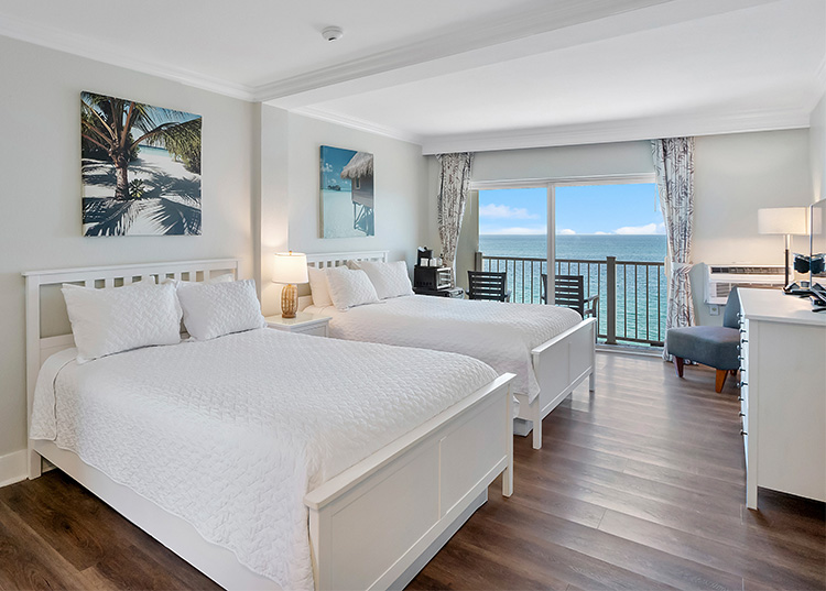 a room with two beds and a view of the ocean