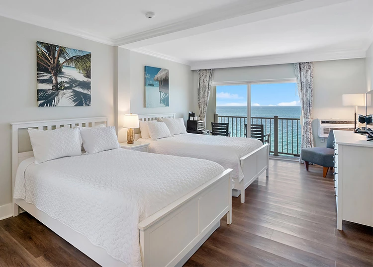 a room with two beds and a view of the ocean