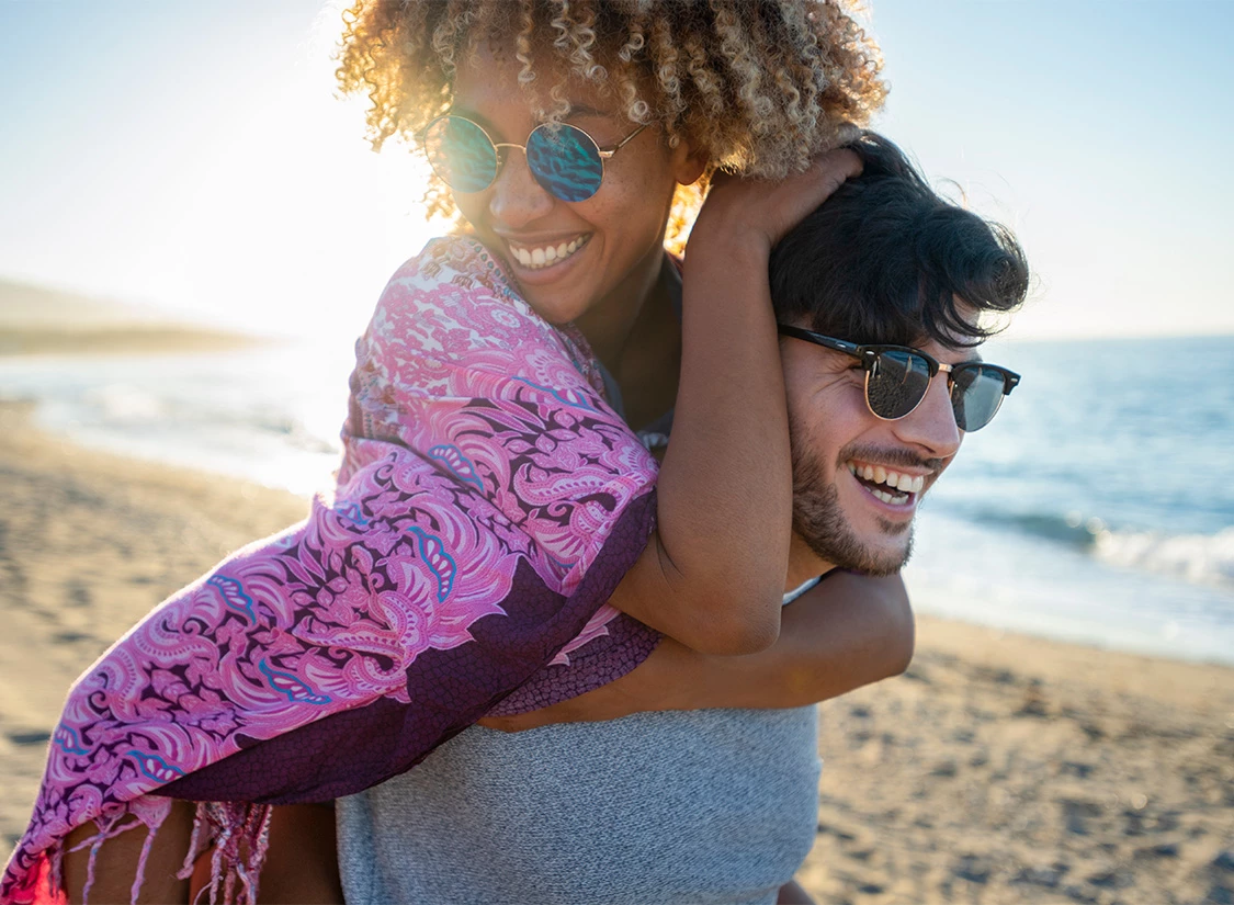 a man carrying a woman on his back on a beach