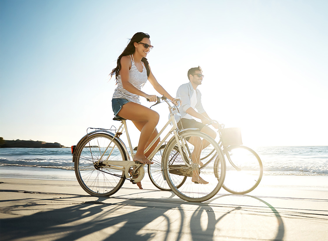 a man and woman riding bicycles on a beach
