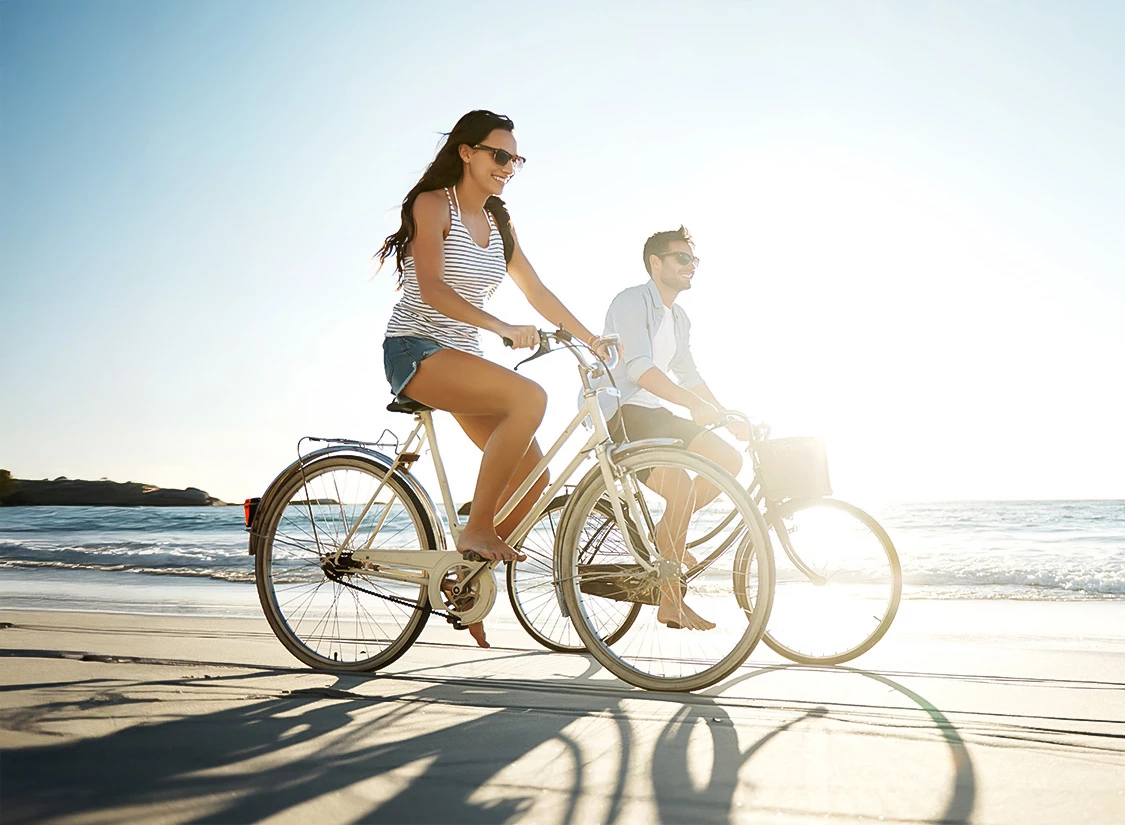 a man and woman riding bicycles on a beach