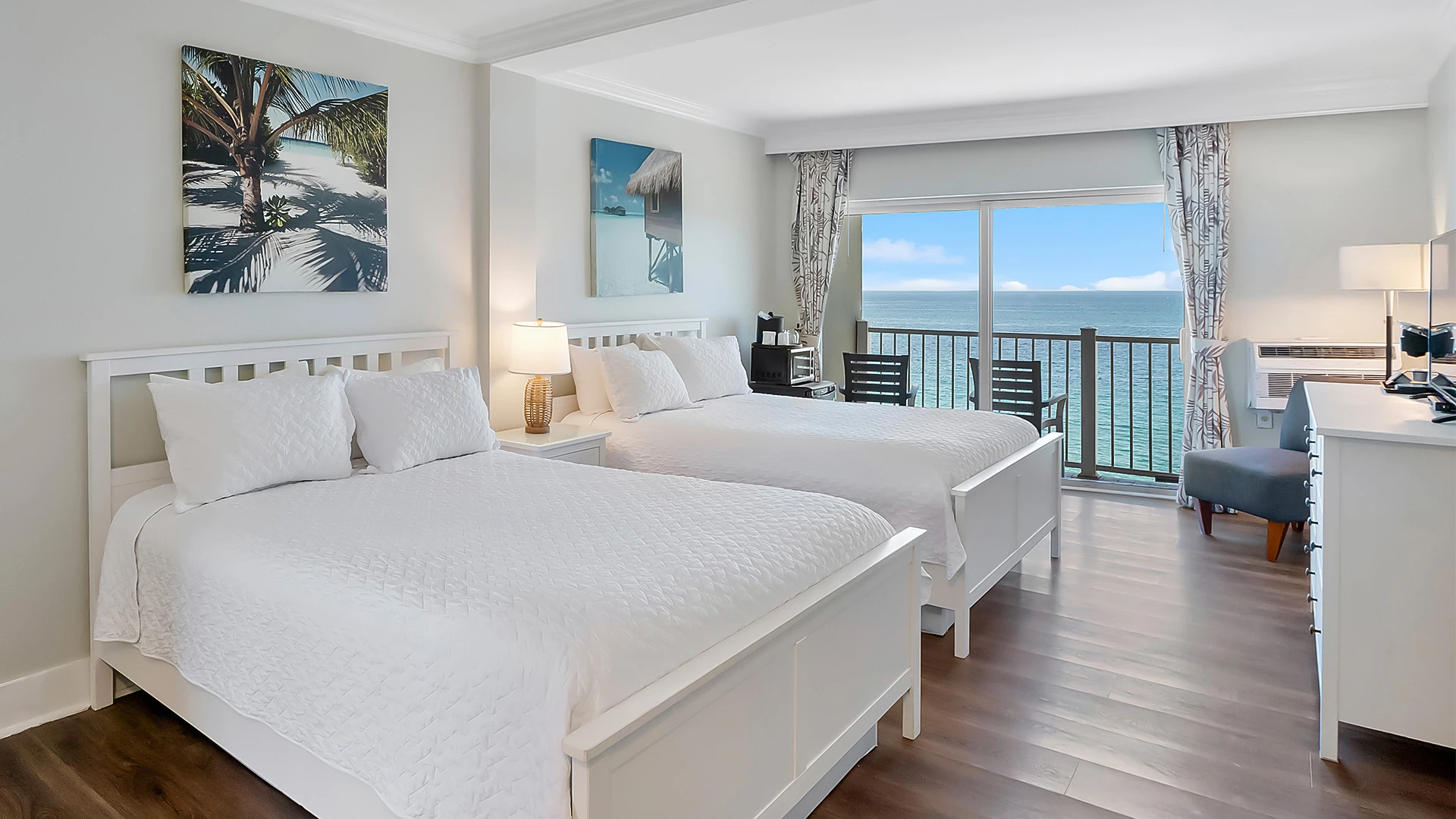 a room with two beds and a balcony overlooking the ocean