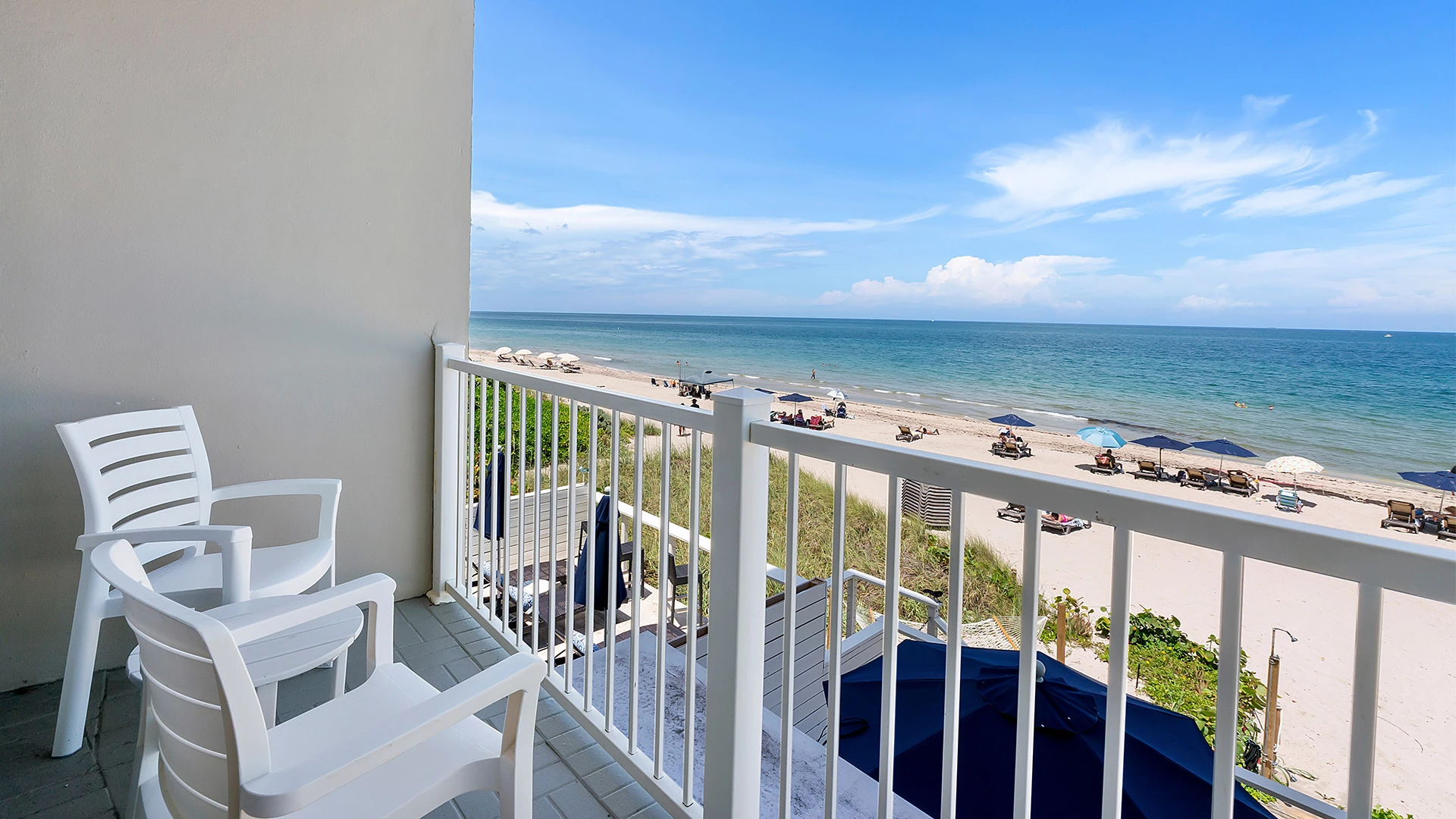 a balcony with chairs and a beach view