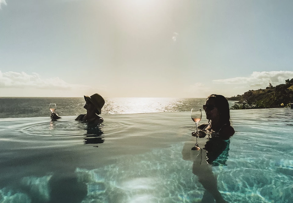 a group of people in a pool with wine glasses