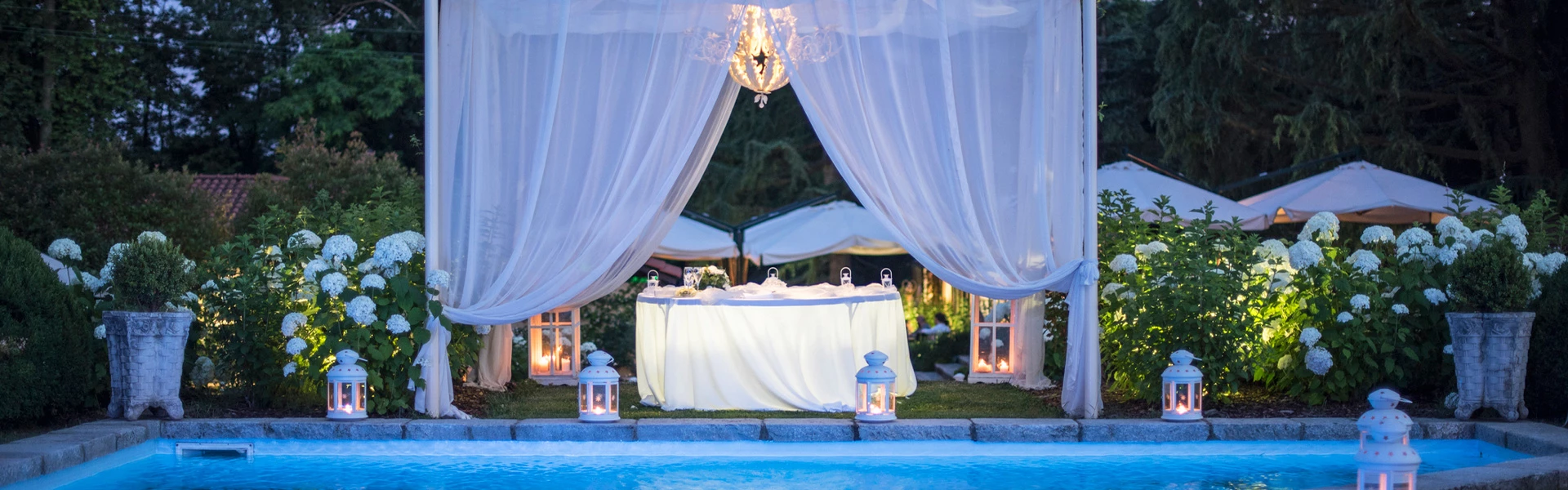 a pool with a white tent and white flowers