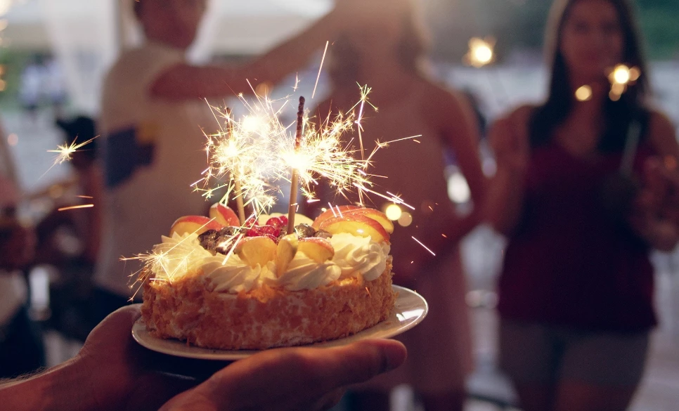 a person holding a cake with sparklers