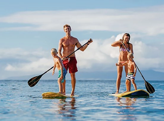 Couple paddle-boarding on two boards with children