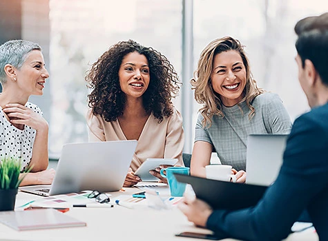 women huddling at a conference room with computers and graphics