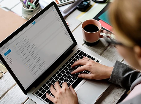 woman checking email at a wooden desk