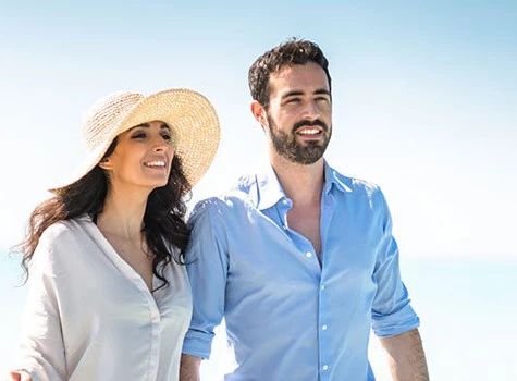 woman and man walking the beach with a blue sky