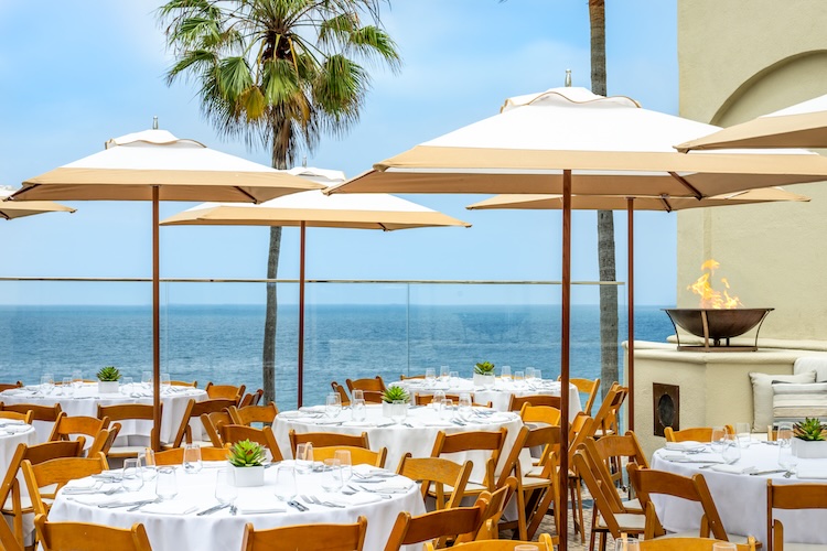 tables and chairs outside with umbrellas and palm trees