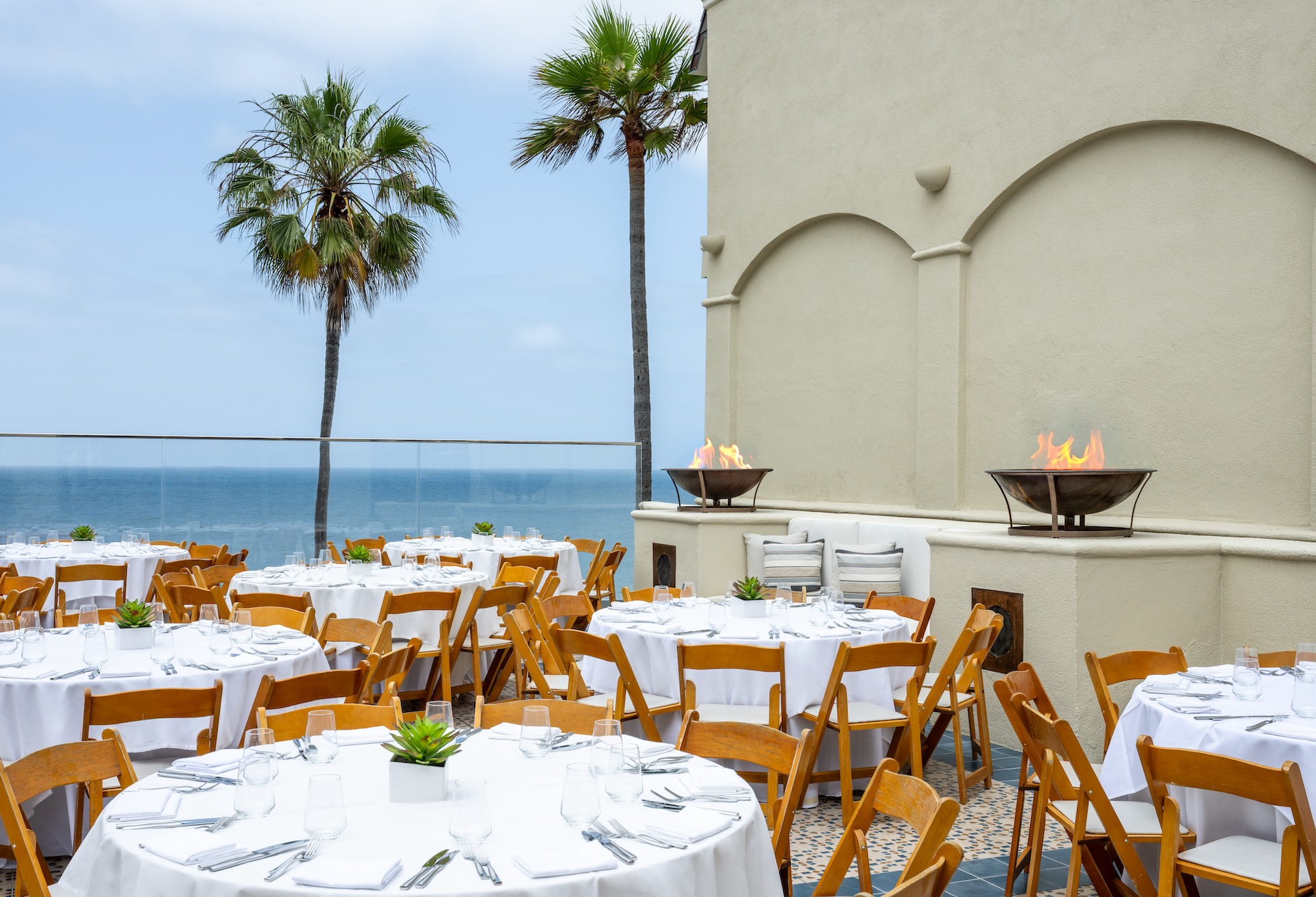 a set tables and chairs outside with a fire pit and palm trees