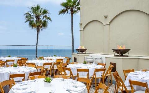 a set tables and chairs outside with a fire pit and palm trees