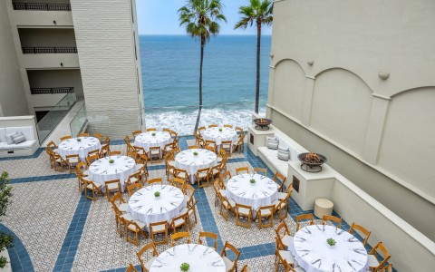 a group of tables and chairs on a patio overlooking the ocean