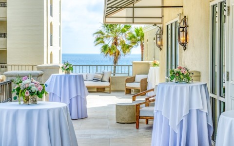 a patio with tables and chairs and a view of the ocean