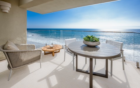 a patio with a table and chairs overlooking the ocean