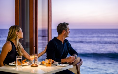 a man and woman sitting at a table with food and drinks