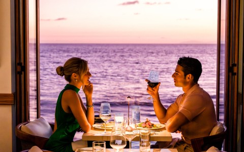 a man and woman sitting at a table with food and drinks