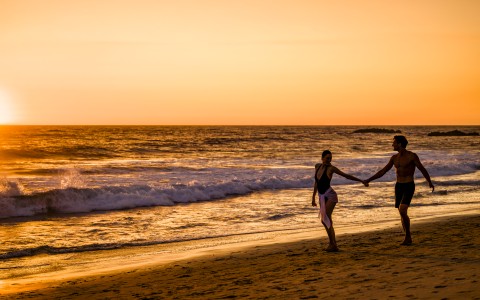 a man and woman holding hands on a beach