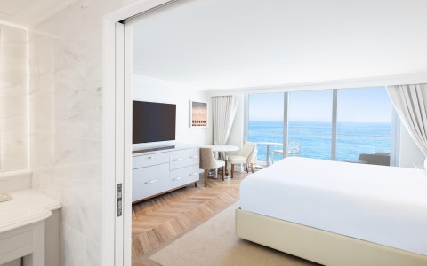 a bedroom with a large window overlooking the ocean
