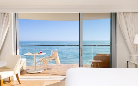 a room with a table and chairs overlooking the ocean