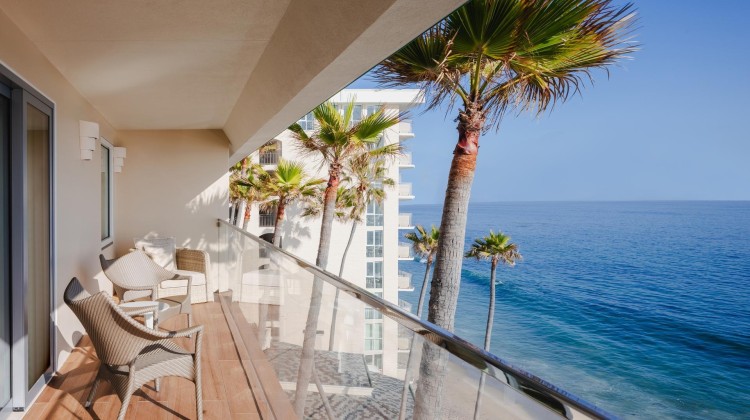 a balcony with palm trees and a beach