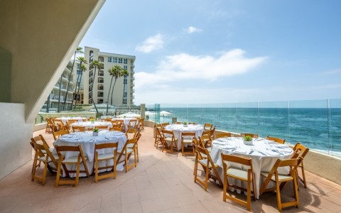 a restaurant with tables and chairs on a patio overlooking the ocean