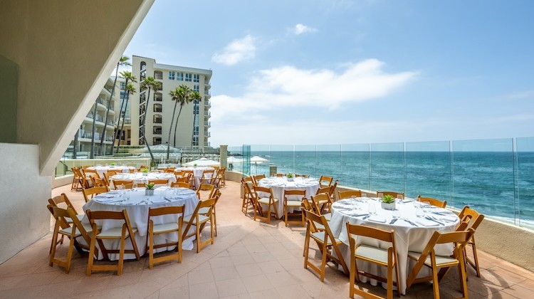 a restaurant with tables and chairs on a patio overlooking the ocean