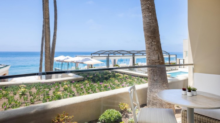 a table and chairs on a balcony overlooking a beach