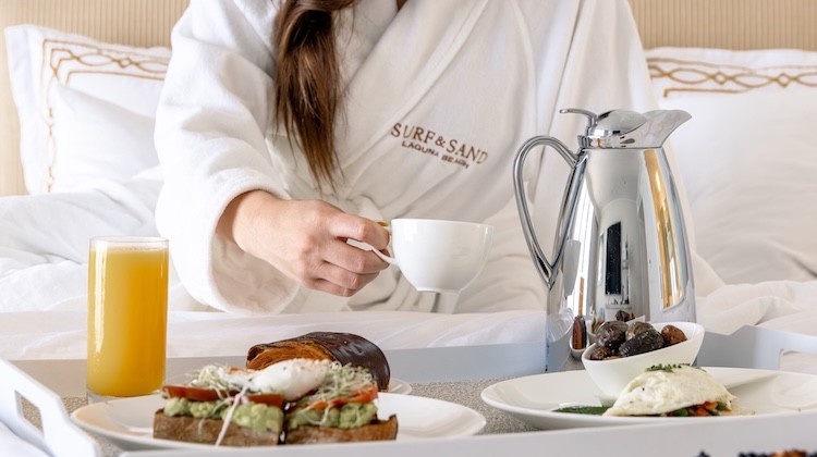 a person in a robe holding a cup of coffee and a plate of food