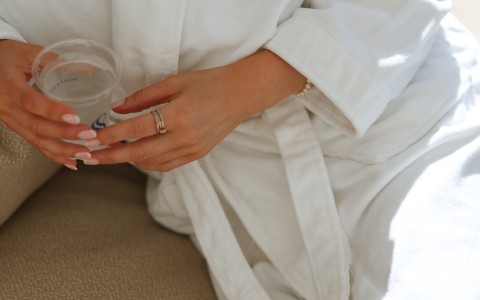 a person in a white robe holding a clear plastic cup