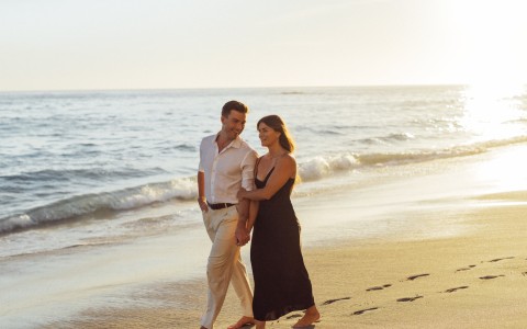 a man and woman holding hands on a beach
