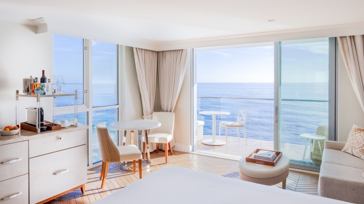 a room with a bed and chairs and a glass door