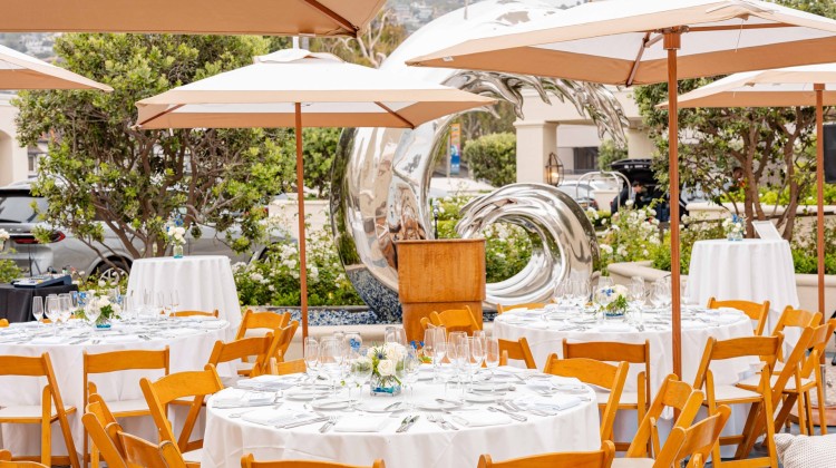 a group of tables and chairs outside with umbrellas