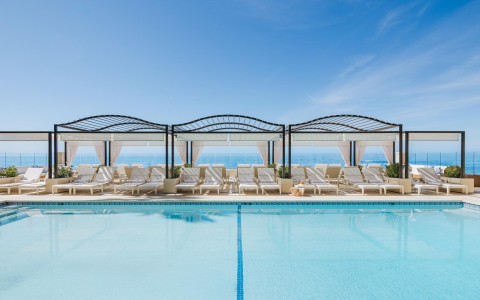 a pool with lounge chairs and a large body of water