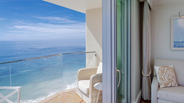 a room with a chair and a glass railing overlooking the ocean